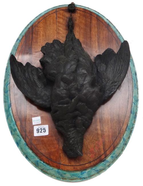 A pair of patinated spelter game birds, early 20th century, each modelled and cast deceased and hanging, mounted on an oval wooden plinth, indistinctl