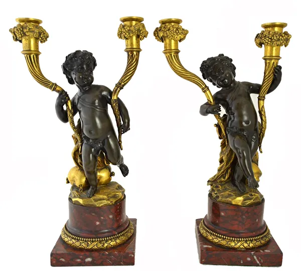 A pair of bronze and ormolu putto candlesticks on red marble plinths, 42cm high.  Illustrated