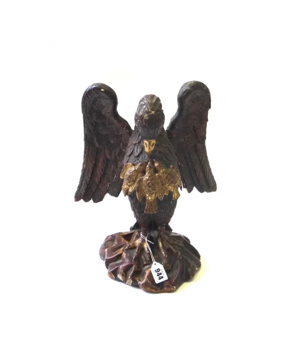 A polychrome painted carved wooden bird, 18th century, depicted with wings outstretched feeding her young, on a rocky base, 35.5cm high.