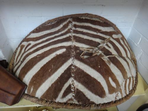 A World War Two flying jacket (a.f), a Zulu zebra skin shield, a 19th century pistol and a World War One leather holster. (4)