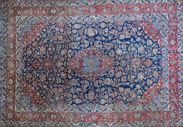 A Kashan carpet, early 20th century, with blue field and central red and blue medallion, multiple borders, 368cm x 262cm.  Illustrated