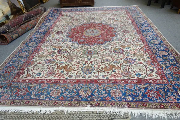 A Tabriz carpet, Persian, the ivory field with a bold faceted madder medallion, all with floral sprays, birds and animals, am indigo palmette and flor