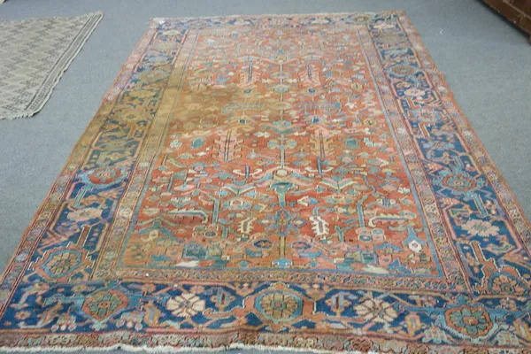 An Heriz carpet, Persian, the madder field with an allover floral spray design, an indigo palmette and flower border, 280cm x 200cm.