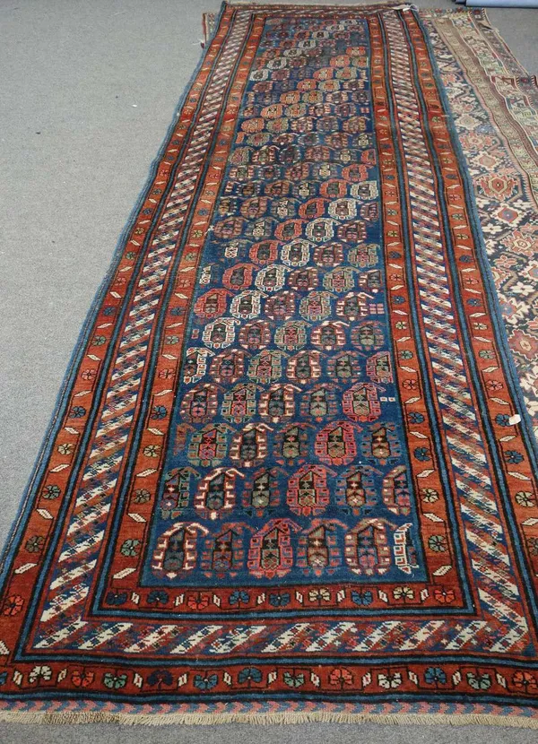 A Gendge runner, Caucasian, the indigo field with diagonal bands of coloured botehs, a banded border, 374cm x 114cm.