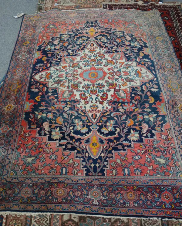 A Malayer rug, Persian, the indigo field with a bold ivory medallion, madder spandrels, all with angular floral sprays, a palmette and vine border, 18