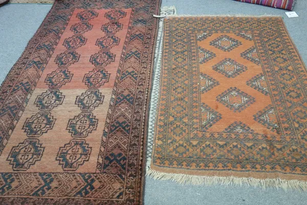 An Afghan rug, the madder field with two columns of eight guls, a hooked border, 215cm x 109cm, together with a golden Afghan rug, 150cm x 100cm. (2)