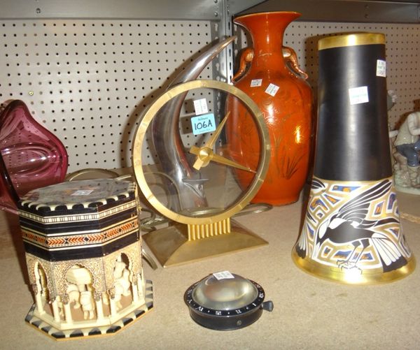 A group of decorative 20th century items, including a glass and metal clock, a metal candle stand in the shape of a bull's horn, an Oriental orange ba