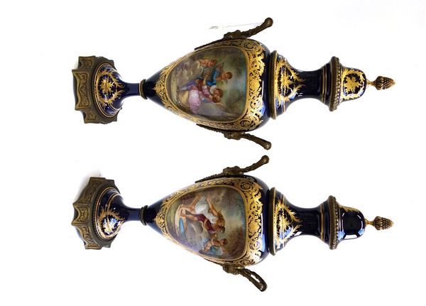 A pair of Sevres style ormolu mounted lidded porcelain vases, circa 1900, decorated with courting couples and cherubic figures within gilt foliate bor