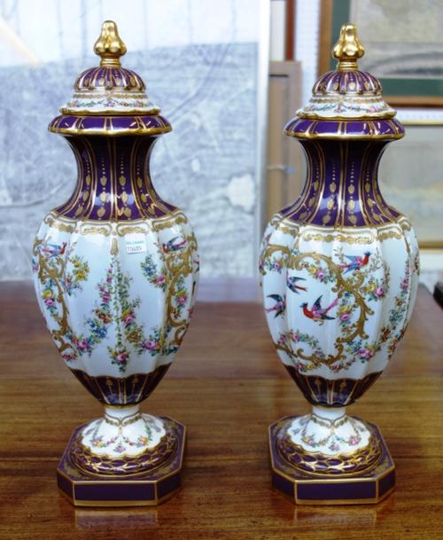 A pair of Sevres style porcelain lidded vases, early 20th century, each of fluted baluster form, decorated with exotic birds and gilt foliate scrolls