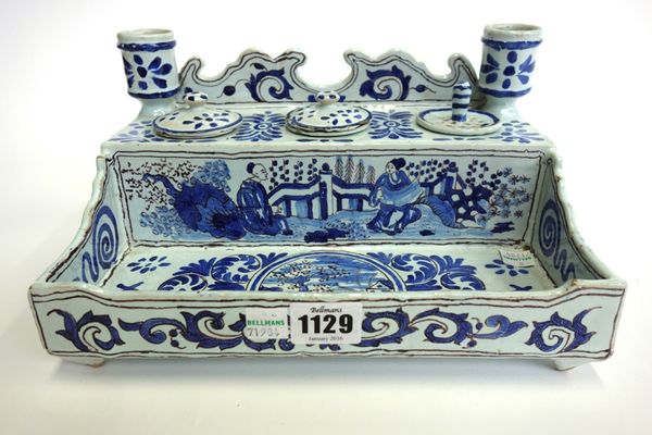 A French faience blue and white desk stand, 19th century, with twin candle sconces and three inkwell recesses over a pen tray, the rectangular body pa