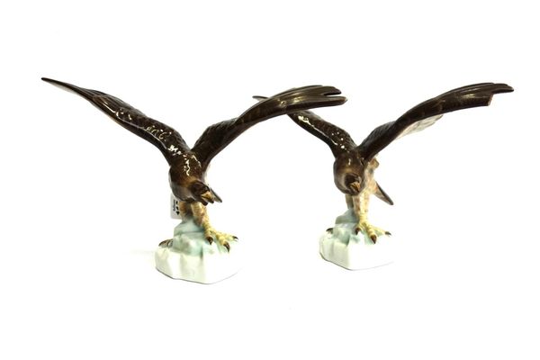 A pair of Herend porcelain birds of prey, each modelled with wings outstretched atop a rocky mound (a.f), 19cm high (2).