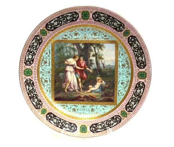 A Vienna style charger, late 19th century, decorated with a classical Cupid scene within a gilt foliate multi-coloured wide border, with spurious blue