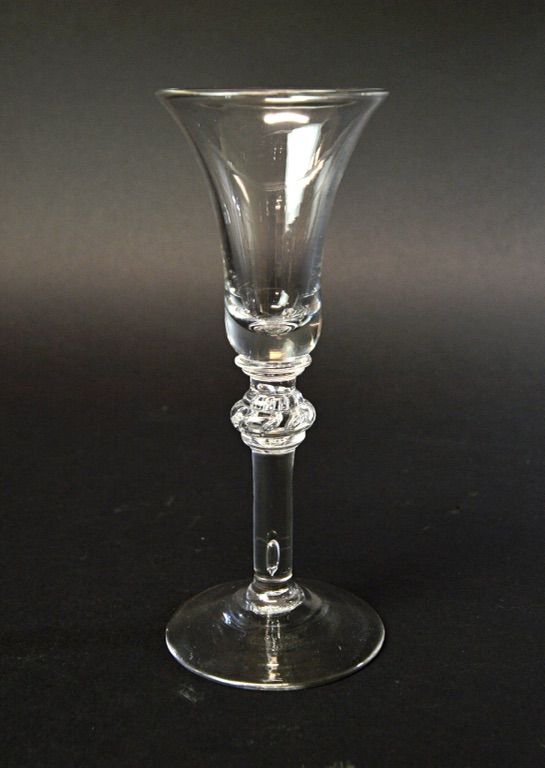 An English wine glass, circa 1740, with bell bowl and teared annulated knop, on a circular foot, 17.6cm high.  Illustrated