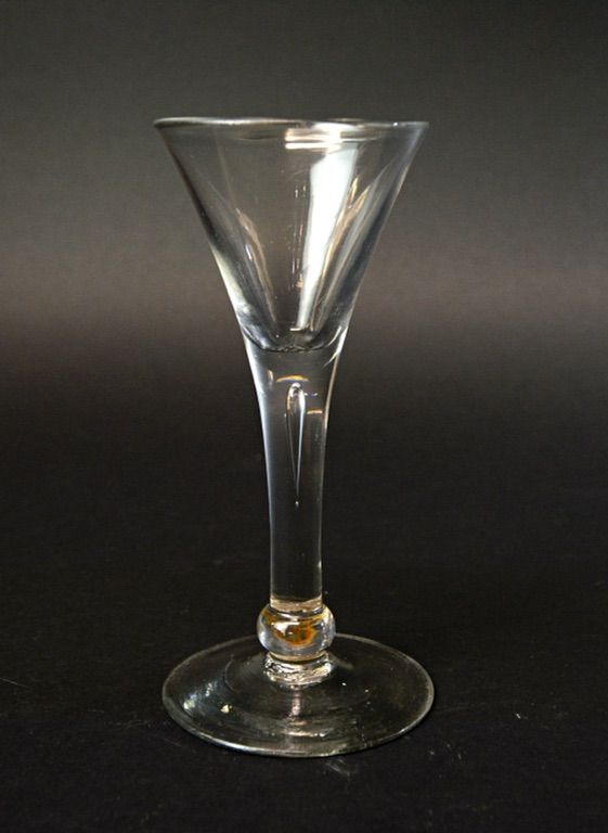An English wine glass, circa 1750, with a teared drawn trumpet bowl and basal knop, on a circular foot, 15cm high.  Illustrated