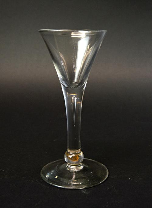 An English wine glass, circa 1750, with a teared drawn trumpet bowl and basal knop, on a circular foot, 15cm high.  Illustrated