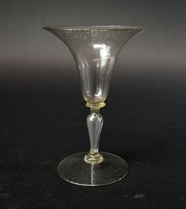 A Facon de Venise wine glass of late 17th century style, with flared trumpet bowl and a hollow shaped stem, on a circular foot, 14.3cm high.  Illustra