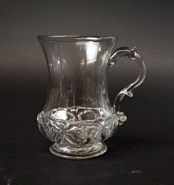 An English glass mug, circa 1760, with pinched waist body and 'nipped diamond waies' decoration to the lower body, on a circular foot, 11.3cm high.  I