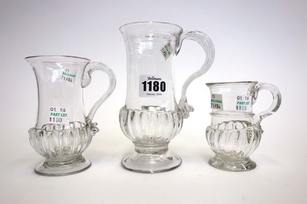 Three English glass mugs, circa 1770, of similar gadrooned form, the larger two both with reeded handles, the smaller with a single band to the body,