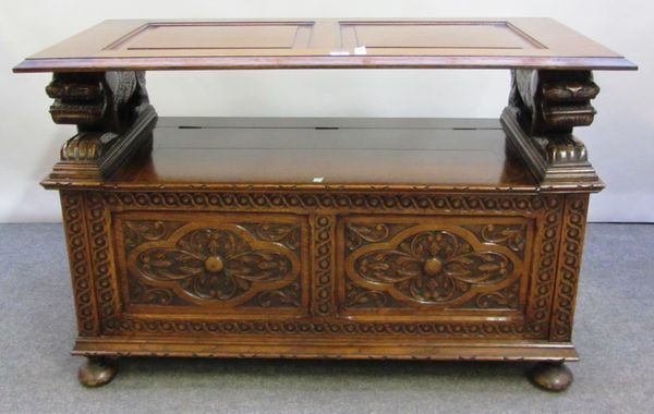 A 20th century carved oak monk's bench with mythical beast mounts on bun feet, 106cm wide.