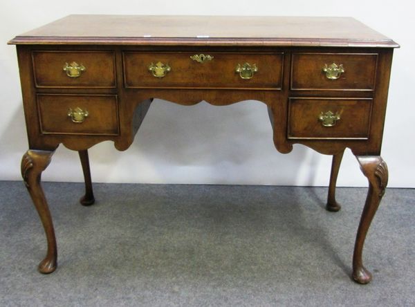 An early 18th century style walnut dressing table with five drawers about the knee, on shell capped cabriole supports, 106cm wide.