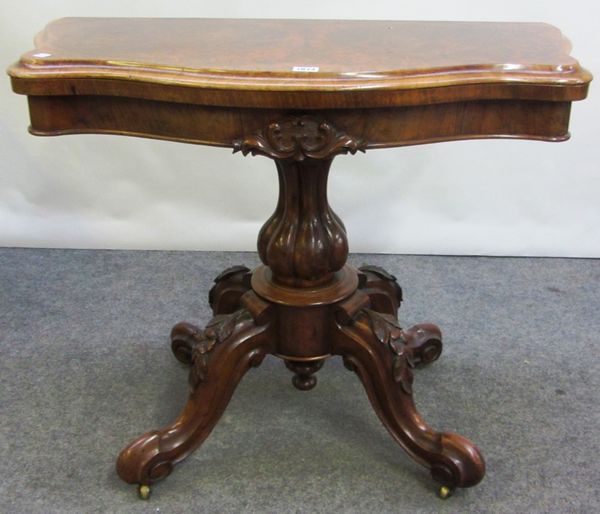 A Victorian figured walnut card table, with serpentine top on baluster reeded column and four carved downswept supports, 90cm wide.