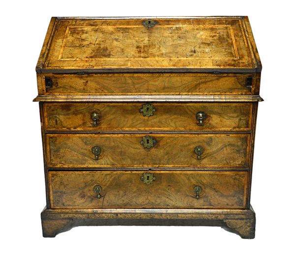 An early 18th century feather banded figured walnut bureau, the fall enclosing a stepped and welled interior over three long graduated drawers, on bra