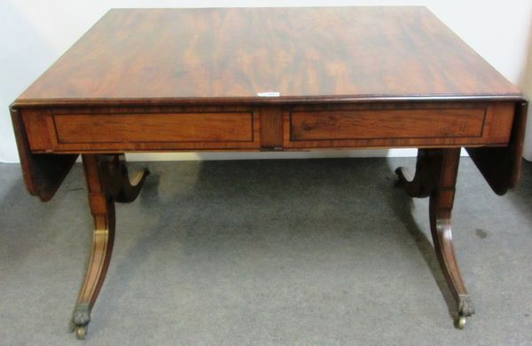 An early 19th century large mahogany sofa table, with shaped drop ends over pair of flush frieze columns, on trestle end standards and four downswept