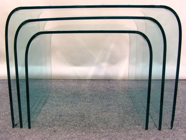 A nest of three 20th century rolled glass occasional tables, the largest 61cm wide.