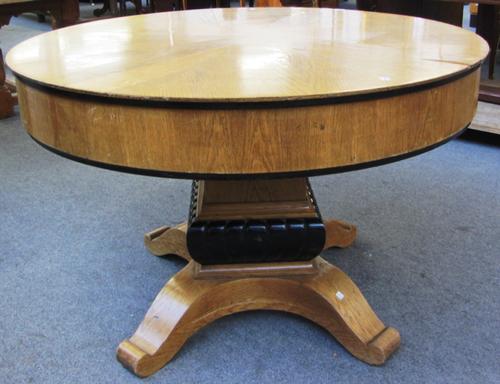 A Biedermeier revival oak circular extending dining table, the frieze dropping to reveal eight Jupes style twist-out additional segmented leaves, rais