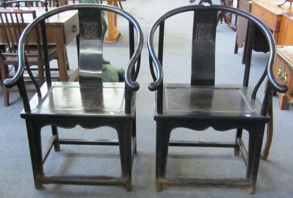 A pair of early 20th century Chinese black lacquer horseshoe back chairs, with solid seats on turned supports.