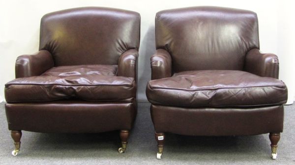 A pair of 20th century brown leather upholstered easy armchairs on turned supports, together with a matching footstool (3).