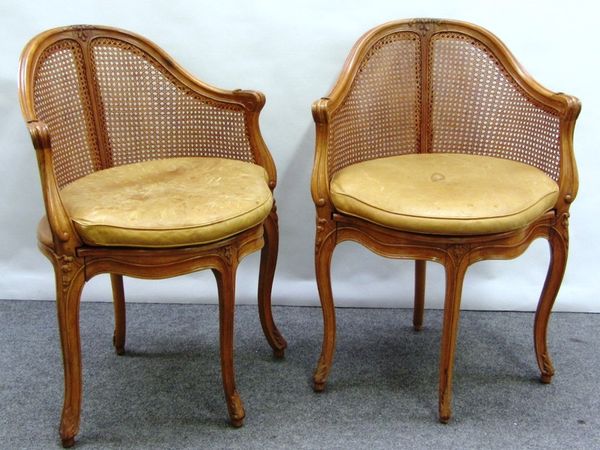 A pair of Louis XV style cane upholstered tub back armchairs, with bow seats on cabriole supports.