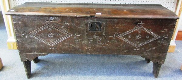 A 17th century oak plank coffer, the carved front panel initialled 'F.R.', with chipwork decoration and slab end supports, 112cm wide.