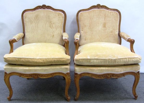 A pair of Louis XV style stained beech fauteuils, each with floral carved crest and serpentine seat, on cabriole supports.