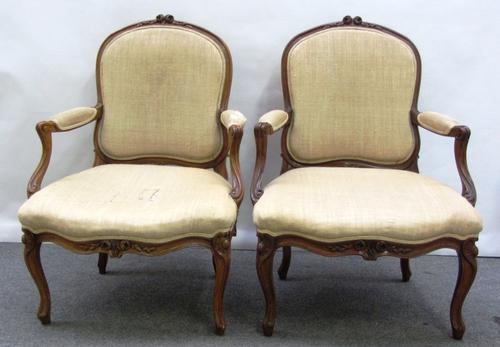 A pair of Louis XV style stained beech fauteuils, each with floral carved crest and serpentine seat, on cabriole supports.