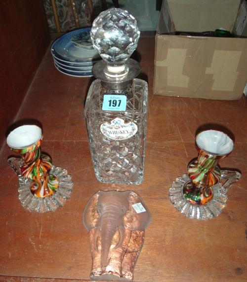 A cut glass decanter with a silver collar, a glass elephant and a pair of coloured glass candlesticks.
