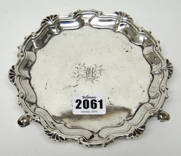 A George II silver waiter, of shaped circular form, with a shell and pie-crust rim, raised on three pad feet, monogram engraved to the centre, diamete