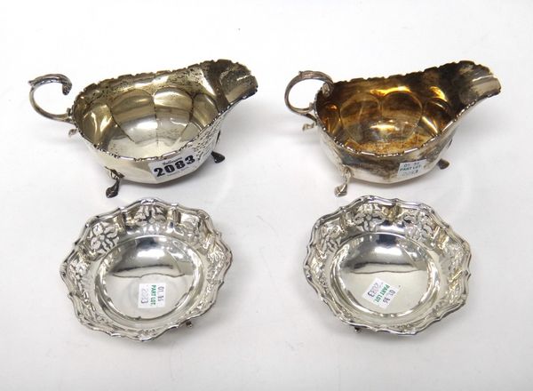 A pair of Scottish silver sauceboats, each of faceted form, with a shaped rim, scrolling handle and raised on three feet, Glasgow 1924 and a pair of s