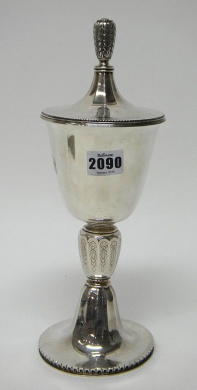 A silver cup and detachable cover, the stem of panelled form, with engraved decoration, on a circular foot, with a decorated border, the cover with a