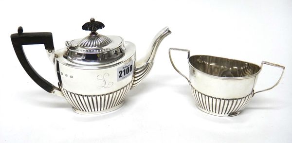 A silver teapot and a matching silver twin handled sugar bowl, each of oval form, with partly fluted decoration, the teapot with wooden fittings, Birm