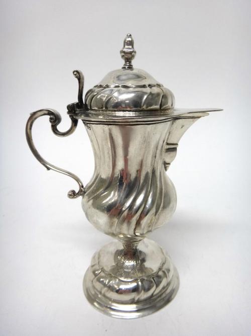 A German silver jug, from an altar cruet, of baluster form, having spiral fluted decoration and with a scrolled thumbpiece, on a circular foot, maker'