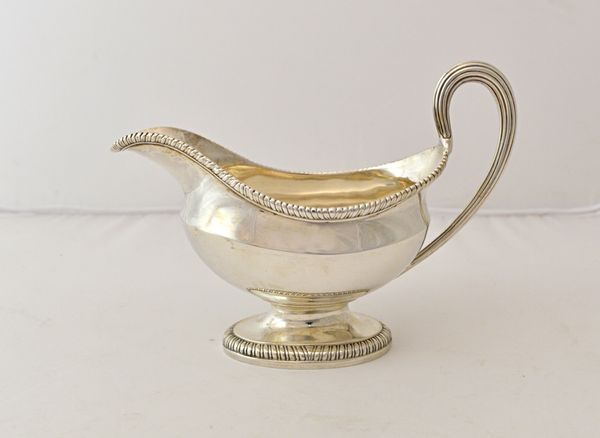 A George III silver sauceboat, of oval form, with a reeded handle, gadrooned rims and on an oval foot, London 1774, weight 383 gms.  Illustrated