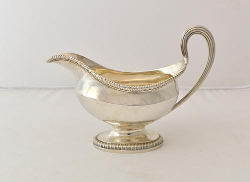A George III silver sauceboat, of oval form, with a reeded handle, gadrooned rims and on an oval foot, London 1774, weight 383 gms.  Illustrated