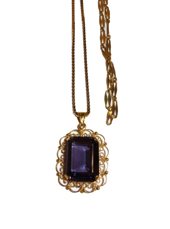 A gold pendant, claw set with a cut cornered rectangular cut synthetic corundum imitating alexandrite, in a scroll pierced filigree border, on a gold