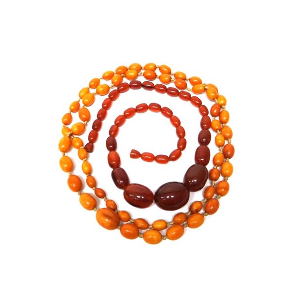 A single row necklace of oval mottled butterscotch coloured amber beads, gross weight 66 gms, an imitation amber costume necklace and a graduated corn