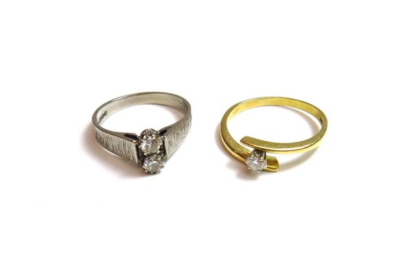 An 18ct white gold and diamond set two stone ring, claw set with circular cut diamonds, between bark textured shoulders, ring size M and a half and an