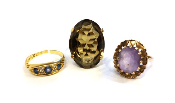 An 18ct gold ring, mounted with three sapphires and with two small pairs of cushion shaped diamonds, a 9ct gold ring, claw set with an oval cut smoky