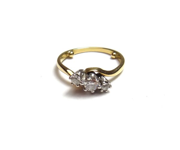 A gold and diamond set three stone ring, claw set with a circular cut diamond at the centre, between two cushion shaped diamonds, in a crossover desig