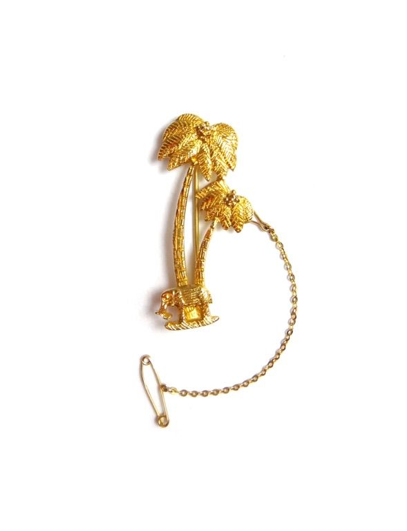 An African gold brooch, designed as two palm trees and an elephant, detailed 18 CT, with a safety chain, weight 10 gms, with a box.