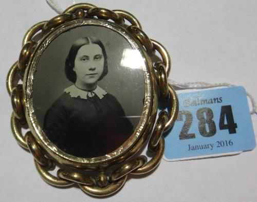 A Victorian gilt metal mounted shaped oval brooch, glazed with two photographic portrait images of a girl and of a young lady.